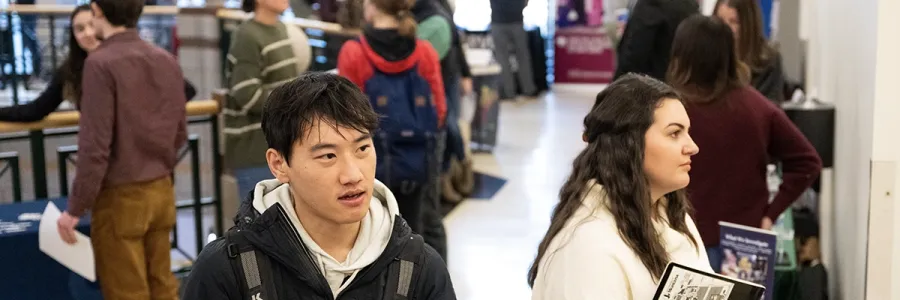 A student shakes the hand of a potential employer at a career fair 
