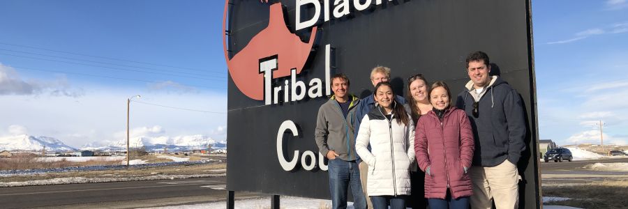 group of people standing in front of Blackfoot Tribal College sign