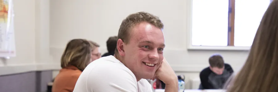 smiling student in a classroom looking at another student