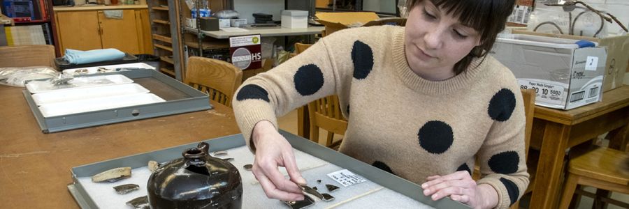 person organizing broken pottery samples on a tray