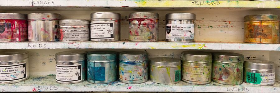 two shelves full of paint covered paint containers