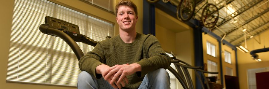 student sitting on treadmill looking at camera