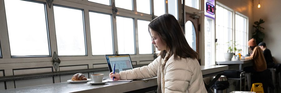 person working in a coffee shop in front of a row of windows