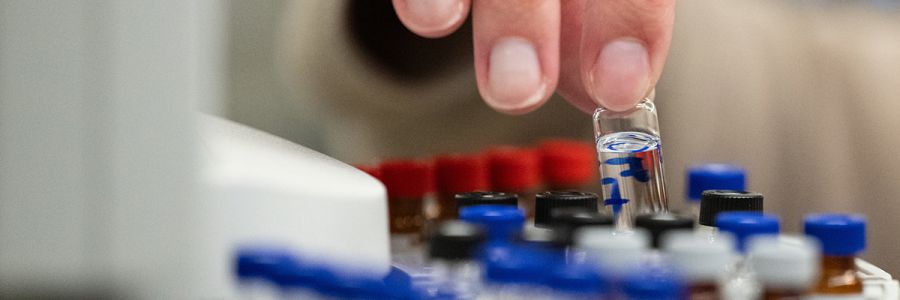 close up view of fingers lifting a single vial out of a tray full of them