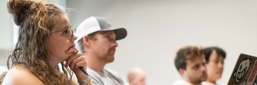 row of students in a classroom looking towards the professor