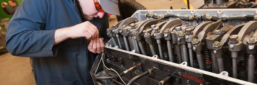 student working closely on a diesel engine