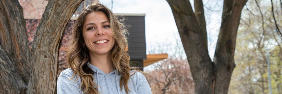 student smiling outside amongst trees on the UM campus
