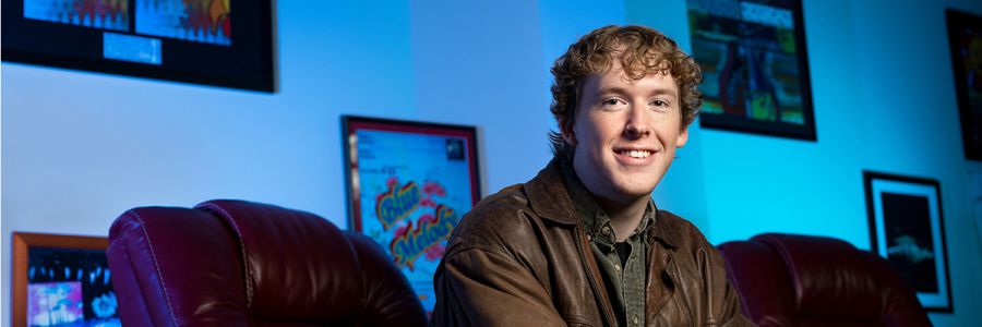 student sitting on leather chair with album art in frames in the background