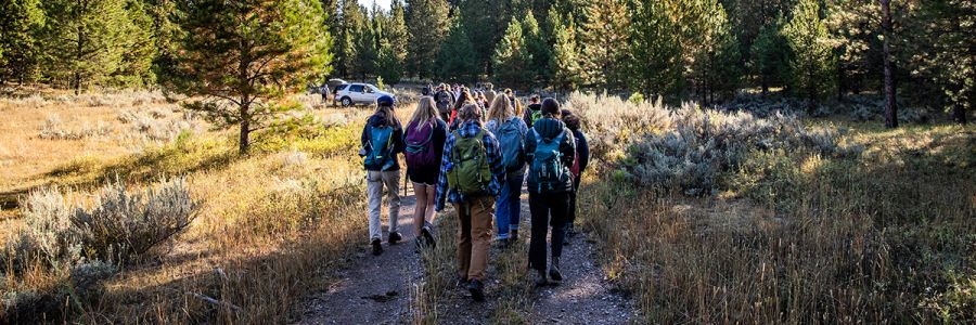 group of people with backpacks walking down a trail in the middle of the image