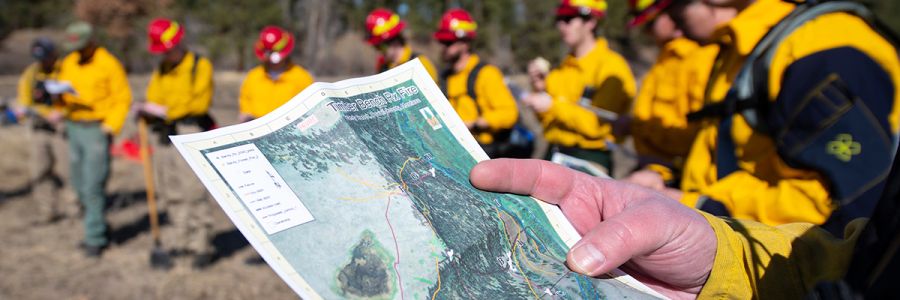 line of wildland firefighters with view of someones hands and a map in the foreground