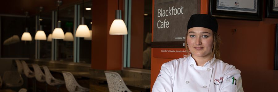 student in chefs clothes standing in the blackfoot cafe