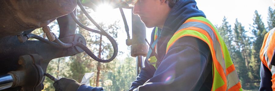 student working on the hydraulics of a construction vehicle