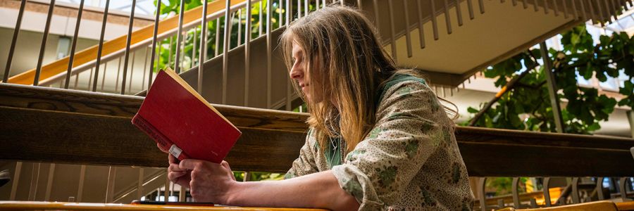 student reading a book while seated inside the university center