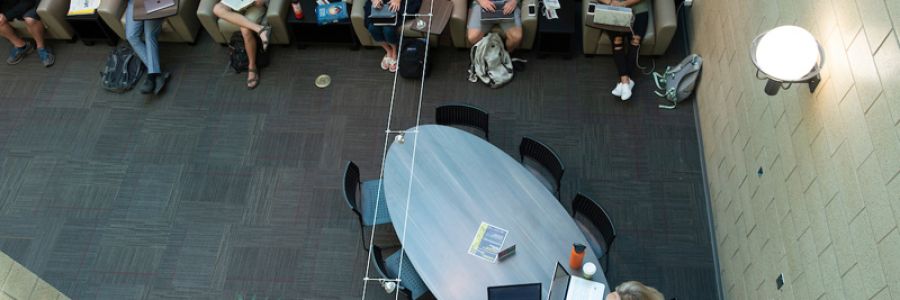 view from above of students working in chairs and at a table in the Gallagher business building