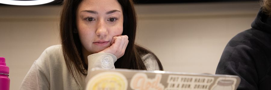 close up view of a student with their hand on their chin while looking at a laptop