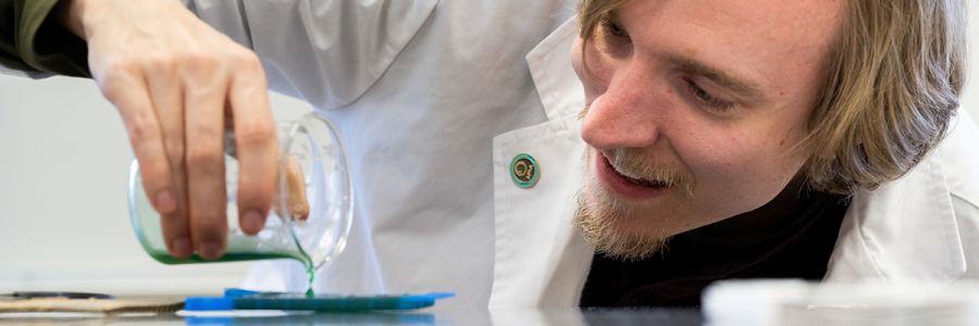 closeup view of a person looking closely at a beaker while pouring out liquid