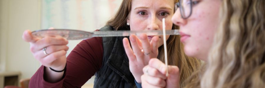 person holding up measuring instruments to another persons face