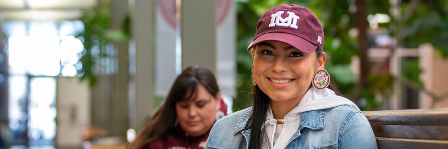 headshot of student sitting inside the UC wearing a maroon UM hat