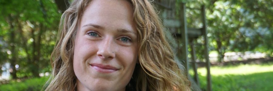 headshot of a smiling student standing outside on the UM campus