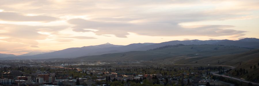 view of Missoula from above with hills and tall mountains far off in the background