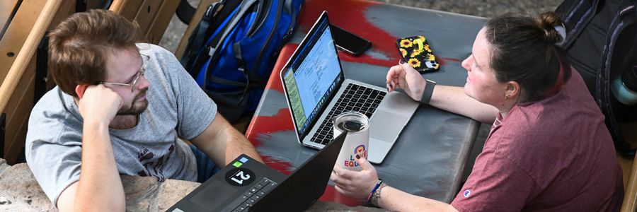 view from above of two people sitting across from each other talking and working on their laptops