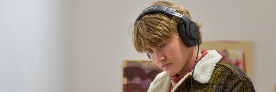 headshot of student wearing headphones and looking down at something outside of the picture