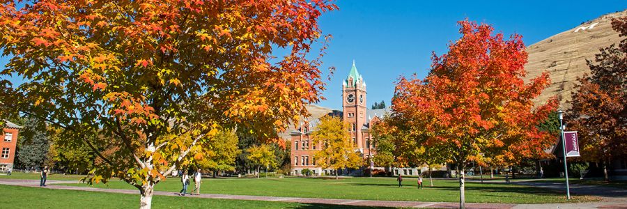 university hall on a sunny day seen from um oval with autumn colored trees