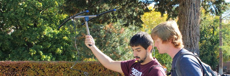student holding up a radio receiver with another student on the UM campus