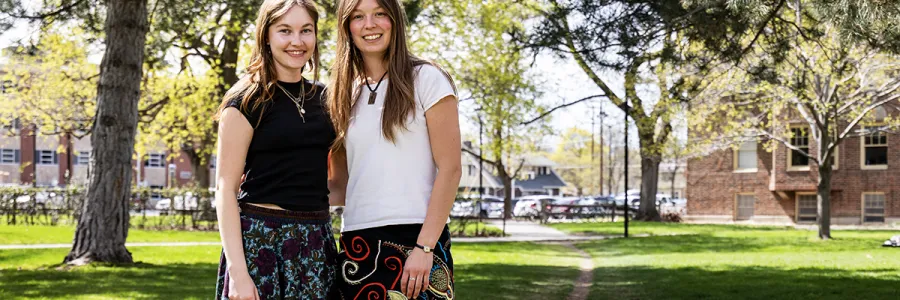 Two female friends stand close to one another 