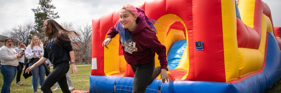 two students jumping out of an inflatable obstacle course