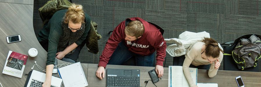 Overhead view of three students working on their laptops