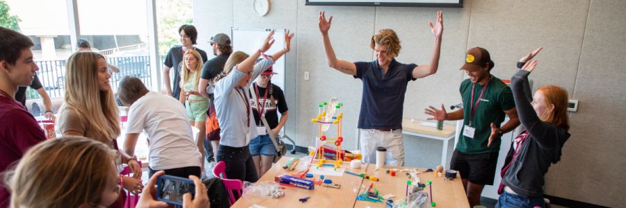 group of students and staff celebrating around a table with a science experiment