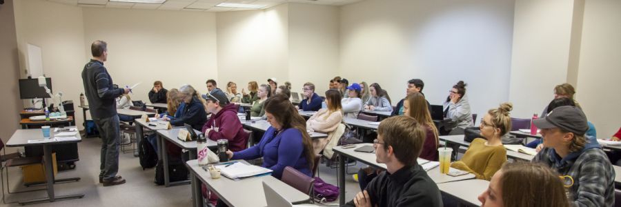 teacher in front of a full classroom viewed from the front