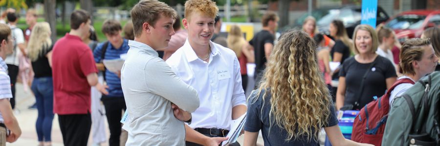 two graduate students talking to another student at an event