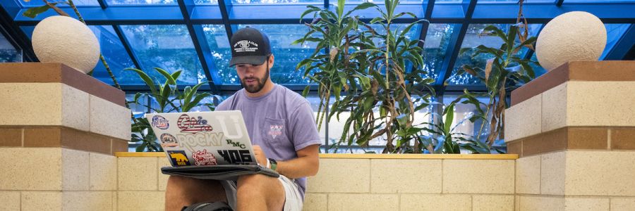 student working on a laptop in the gallagher business building