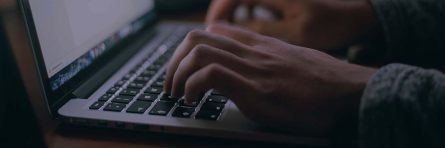 close up view of hands typing on the keyboard of a laptop