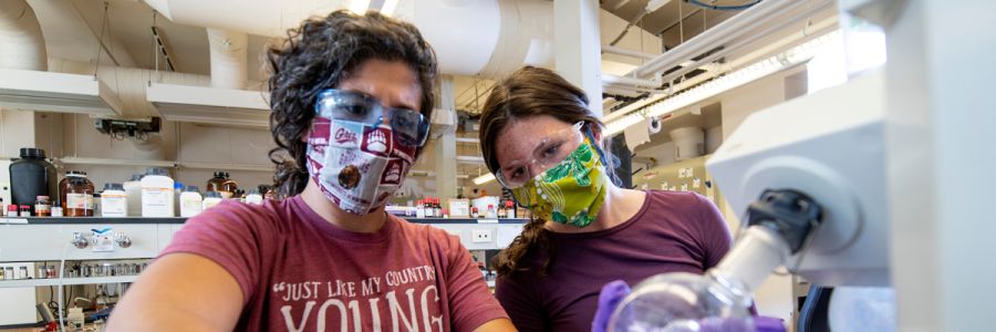two people wearing masks and working on a scientific instrument