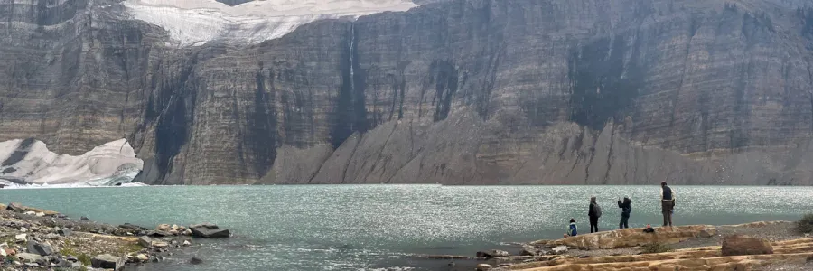 A group of students explore Grinnell Lake in Glacier National Park during the department’s yearly trip, Mountains are in the background with the blue lake in the foreground.
