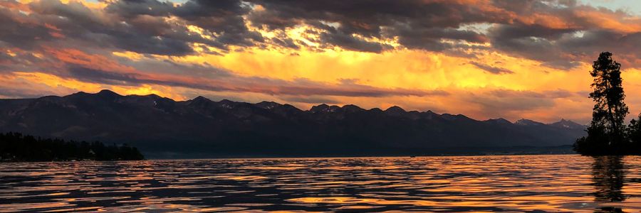 mountain front above a calm lake during a orange tinted sunset