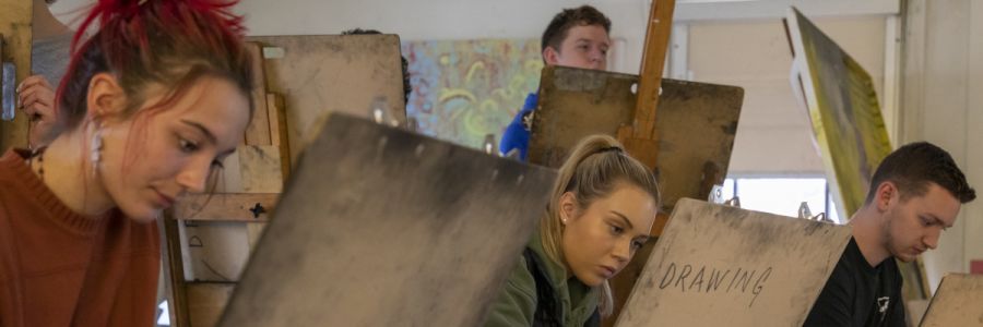 a group of students on multiple levels working on easels 