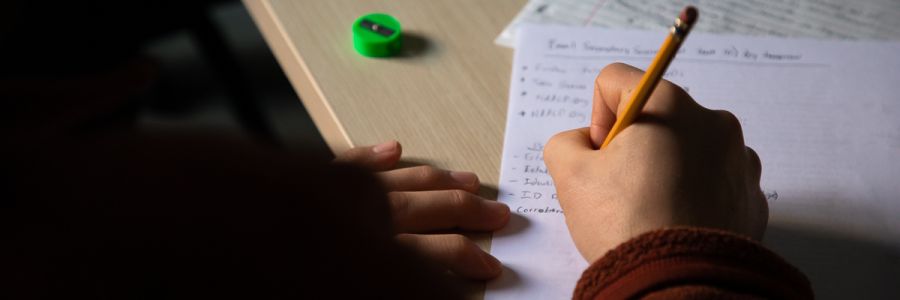 close up view of a students hand making notes on paper