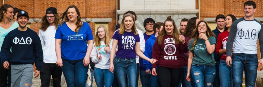 group of students wearing fraternity and sorority shirts walking in a group towards the camera