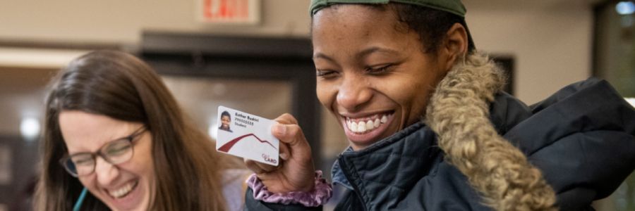 two students smiling while one holds up their Griz card