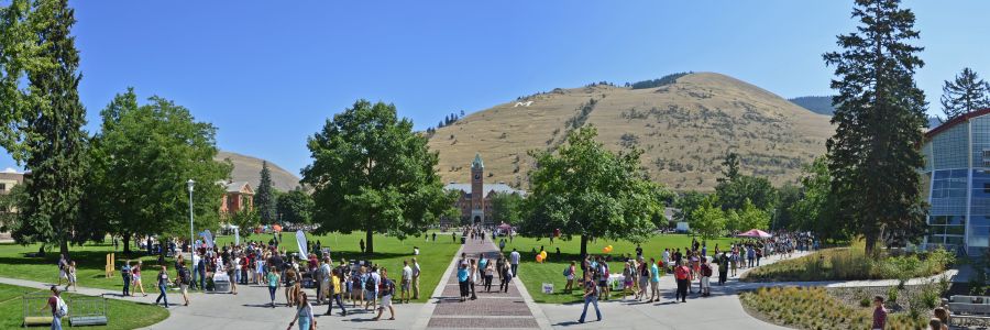 University Hall seen from the other side of the oval with lots of students walking around on a sunny day