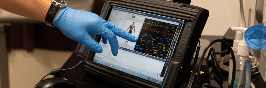 a gloved hand pointing out data on a screen keeping track of various body metrics