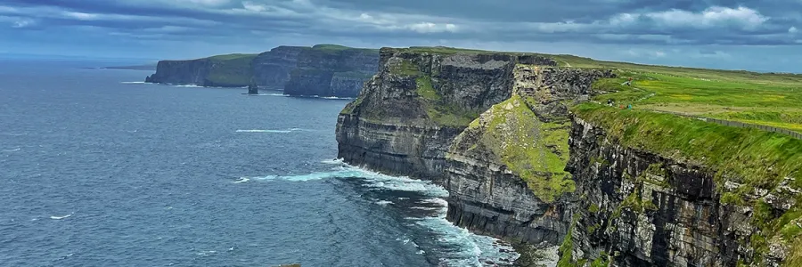 sharp rocky cliffs along a seashore with green plains 