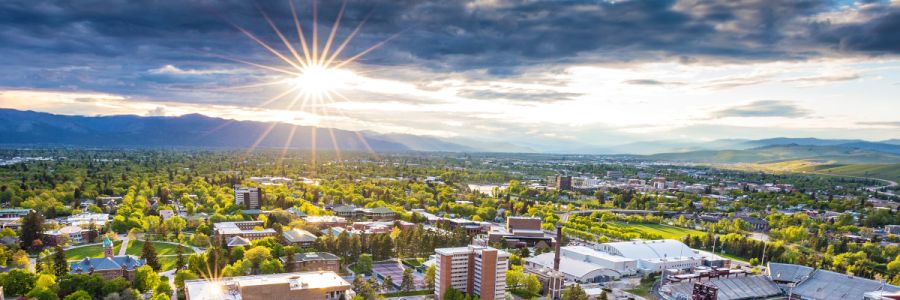 aerial view of campus with the sun shining through clouds in the background