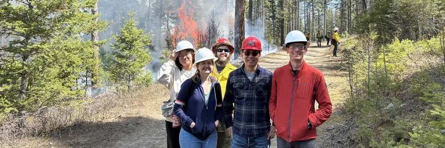 Members of Lu Hu's lab gather for a photo while a forest fire burns in the background