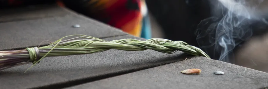 A bundle of sweetgrass being burned on a table