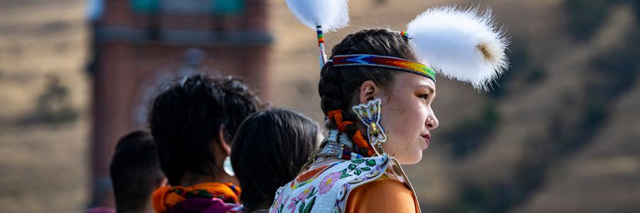 a woman wearing traditional Native American headdress seen from behind in a row with other people